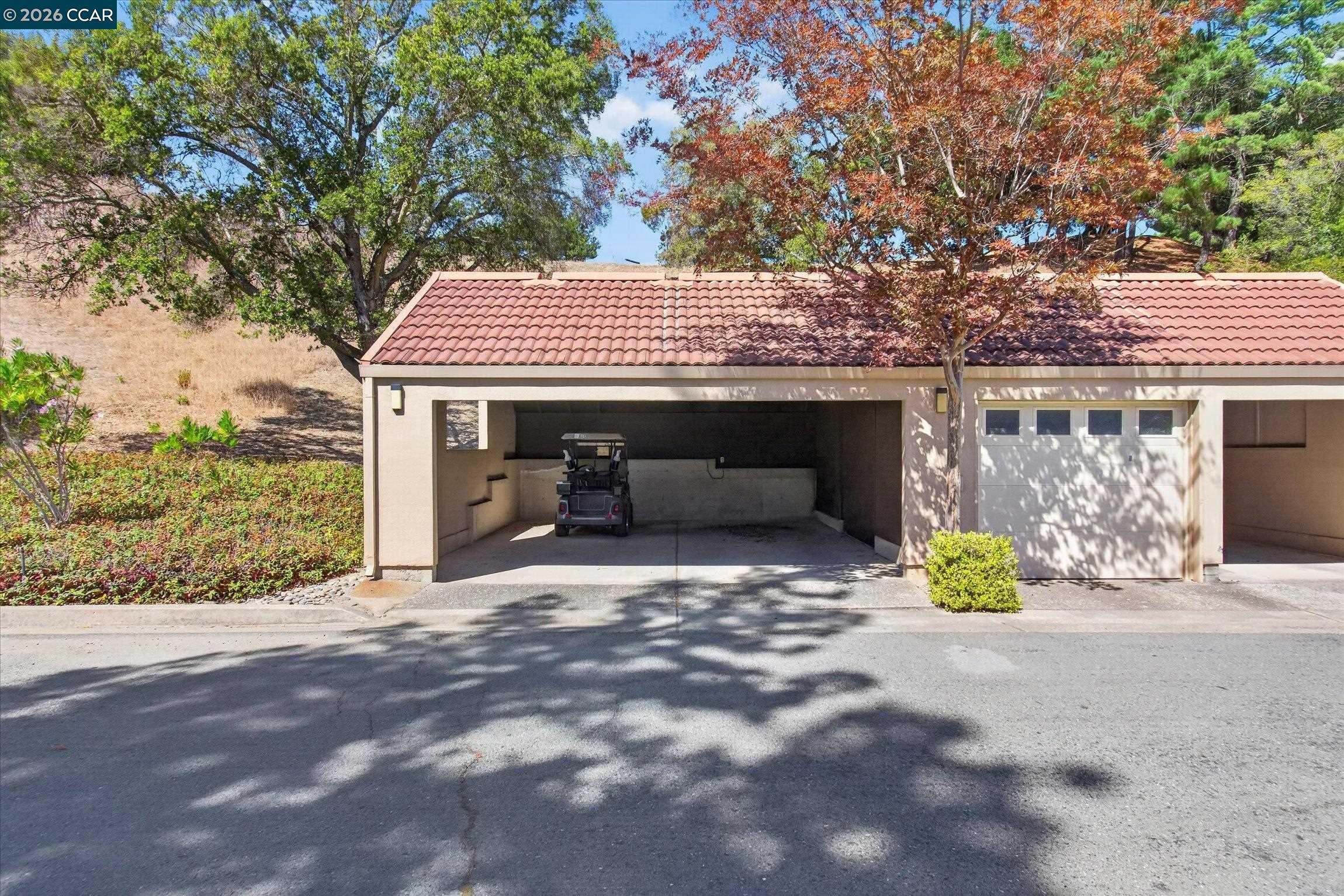 Home exterior with an open garage and golf cart beneath a red tile roof.