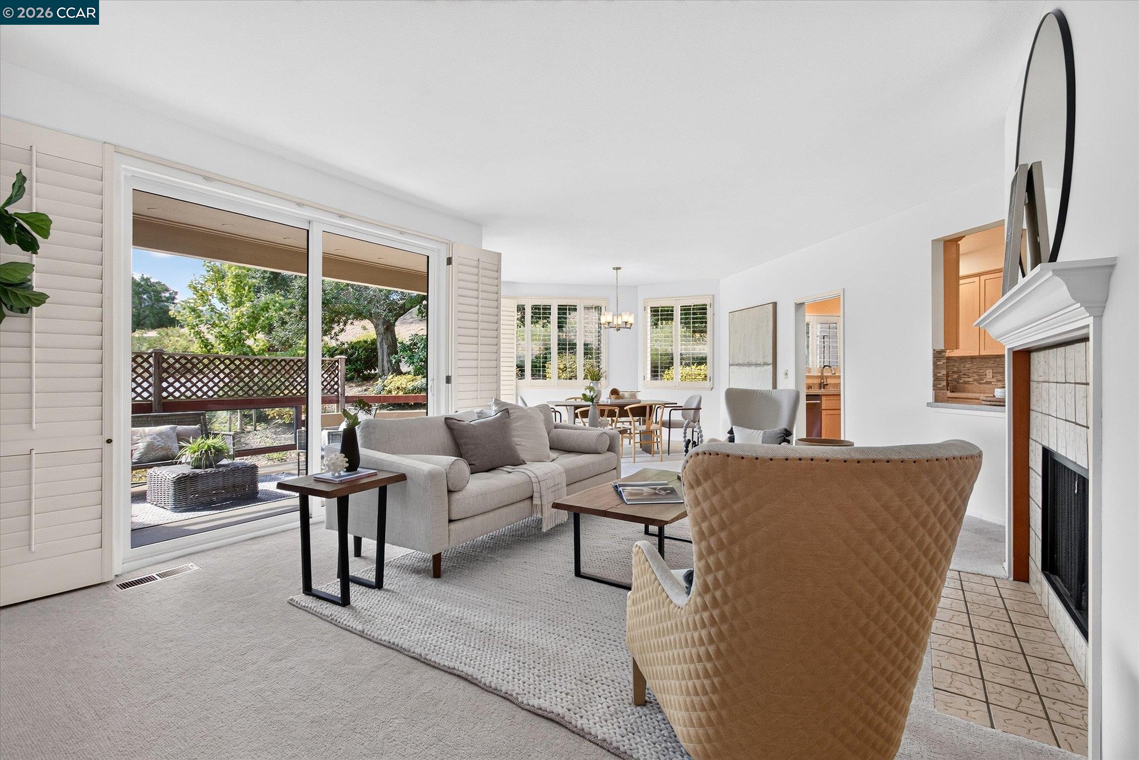 Living room with a fireplace, patio doors, and a dining area beyond.