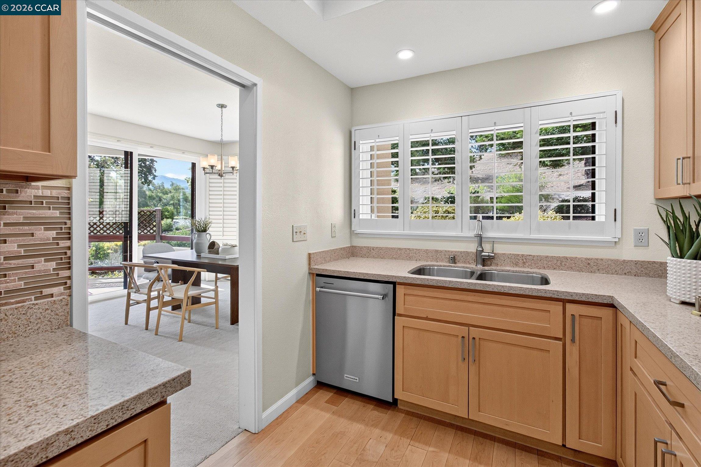 Kitchen with warm wood cabinets, granite counters, plantation shutters, and an adjoining dining area.