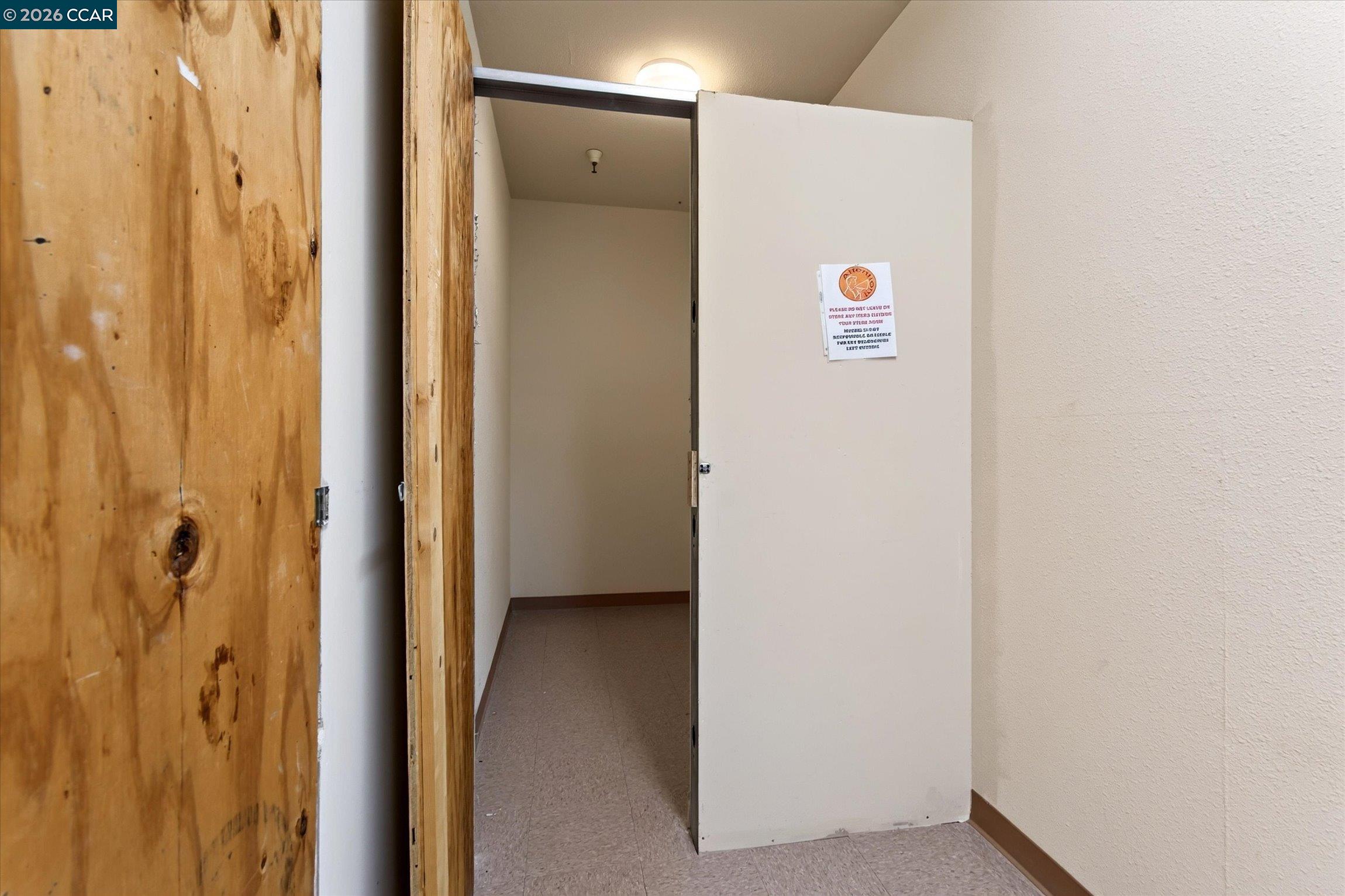 Unfinished entryway with an open white door and exposed plywood framing.