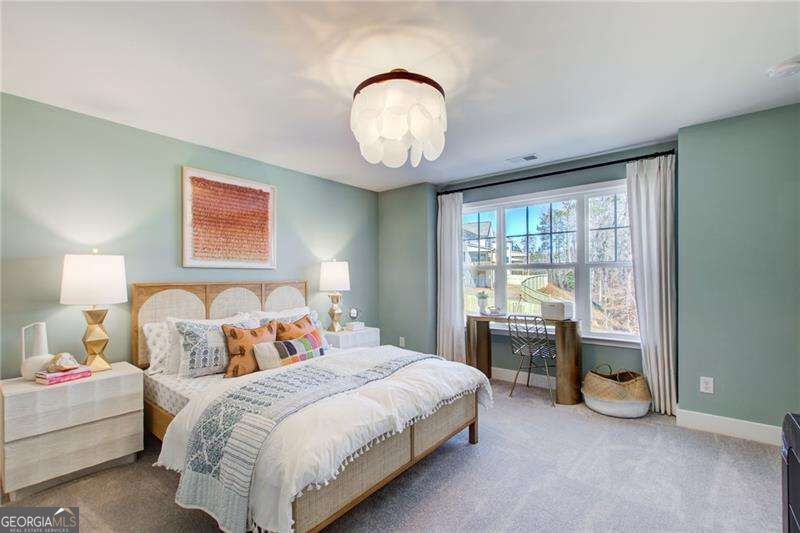 Bedroom with a large bed and a desk beside a wide, curtained window.