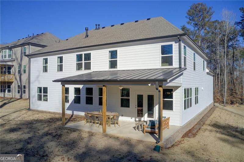 Two-story white house with a covered rear patio and outdoor furniture.