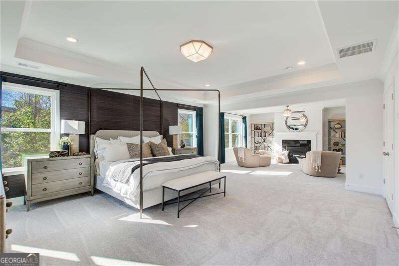 Primary bedroom with a black four-poster bed and a sitting area beside the fireplace.