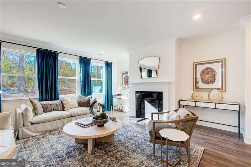 Staged living room with a white fireplace, blue curtains, and a patterned area rug.