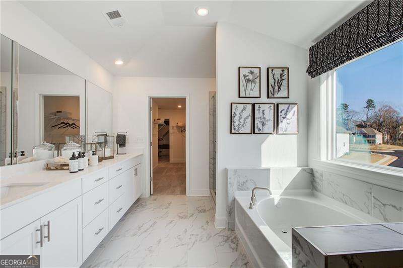 Bathroom with a freestanding tub by a large window and a white double vanity.