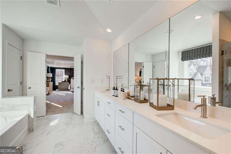 Bright white bathroom with a long mirrored vanity, marble-patterned floor, and sunlit window.