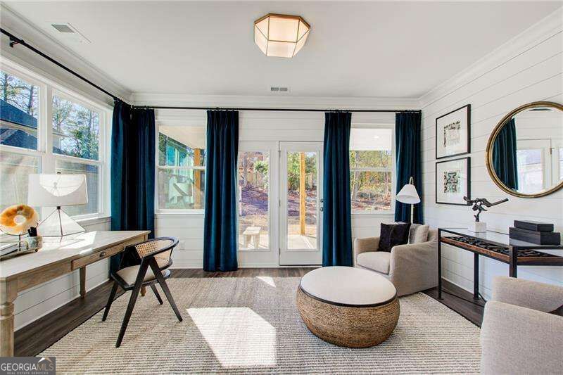 Sunroom with large windows, navy curtains, a desk, and a round woven coffee table.