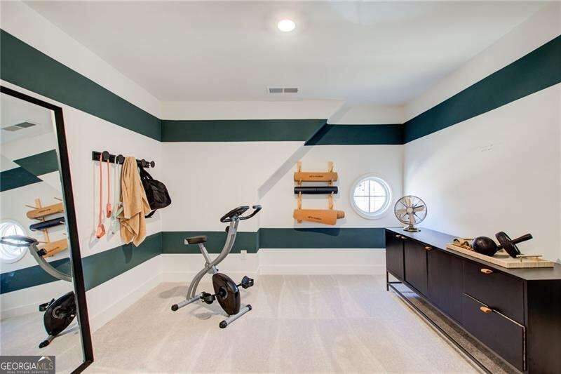 Home gym with a stationary bike, green wall bands, and dark storage cabinets.