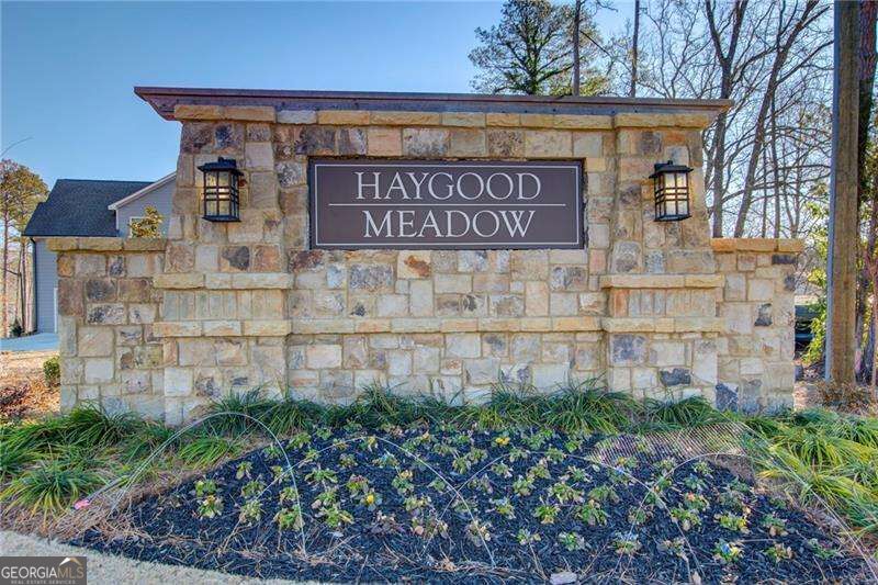 Haygood Meadow neighborhood entrance sign on a stone monument with lanterns and landscaped flower beds.