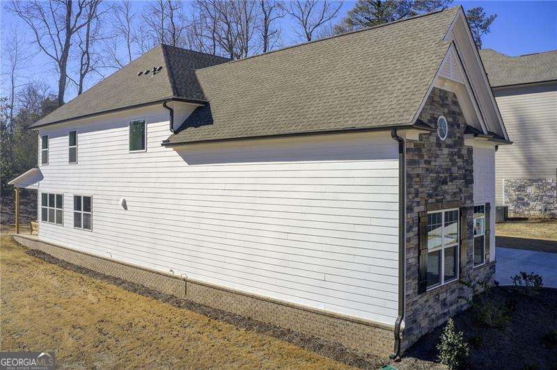 House exterior with white siding, a stone-faced gable, and a broad shingled roof.