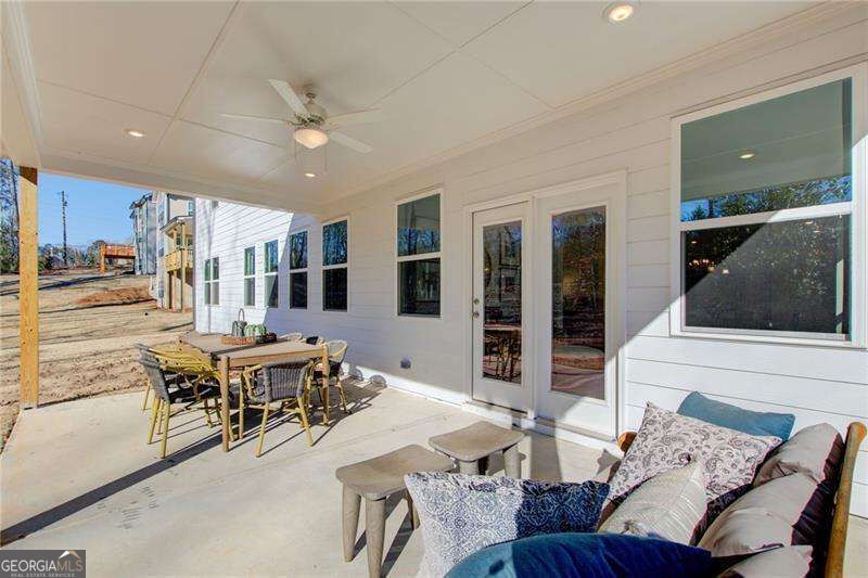 Covered patio with outdoor dining set, ceiling fan, and cushioned seating.