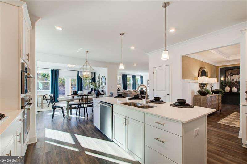 Kitchen with a large white island, pendant lights, and an open dining and living area.
