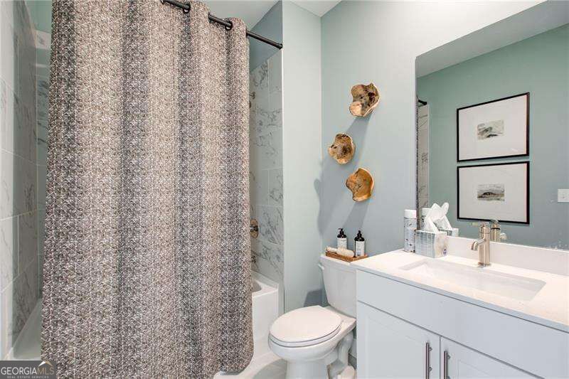 Bathroom with a white vanity, toilet, and textured gray shower curtain.