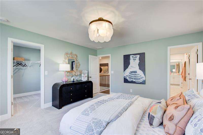 Bedroom with pale green walls, a black dresser, and a bed with patterned white bedding and pink pillows.