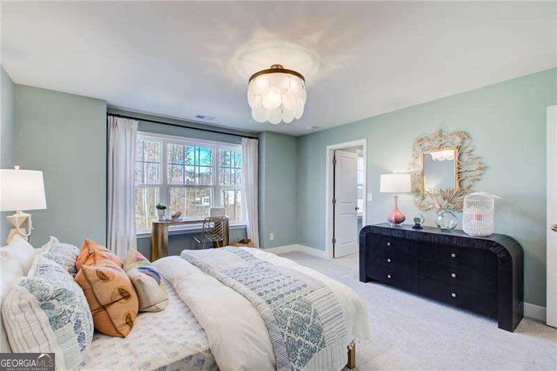 Bedroom with pale blue-green walls, a wide multi-pane window, and a dark curved dresser.