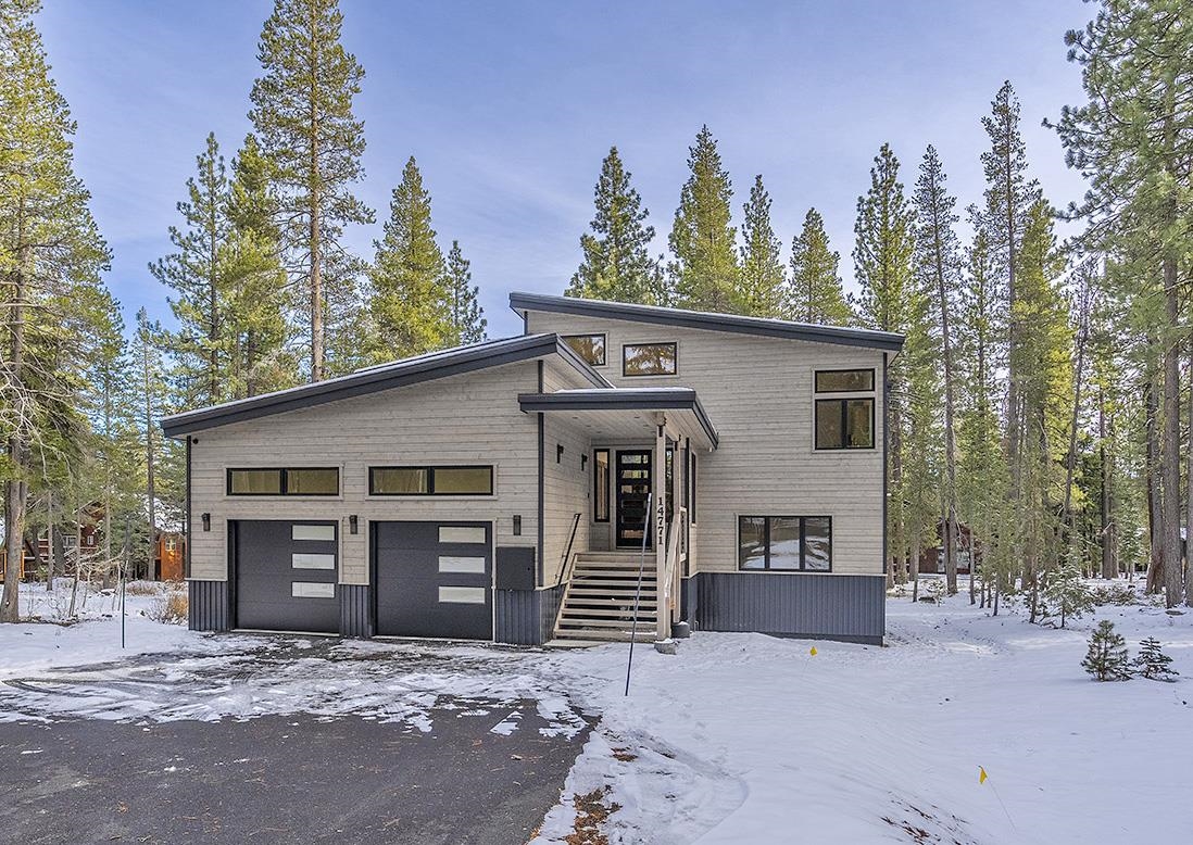 Modern two-story house with a double garage among snowy pines.