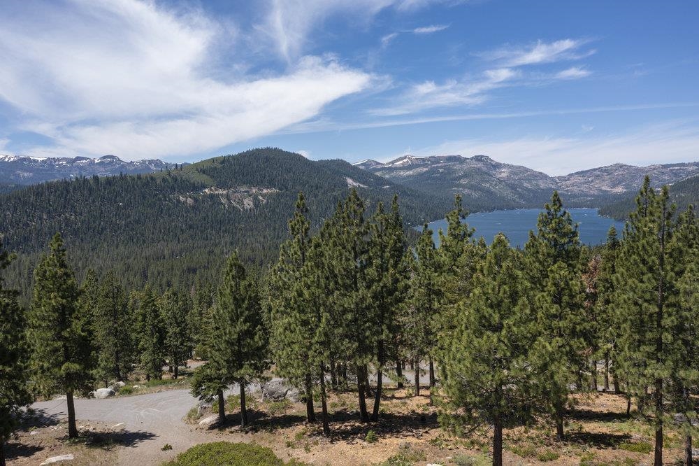 Wooded property overlooking a blue lake and surrounding mountain ranges.
