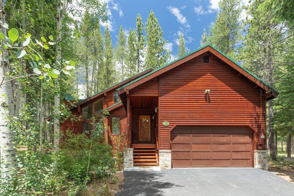 Wood-sided home with an attached two-car garage nestled among tall trees.