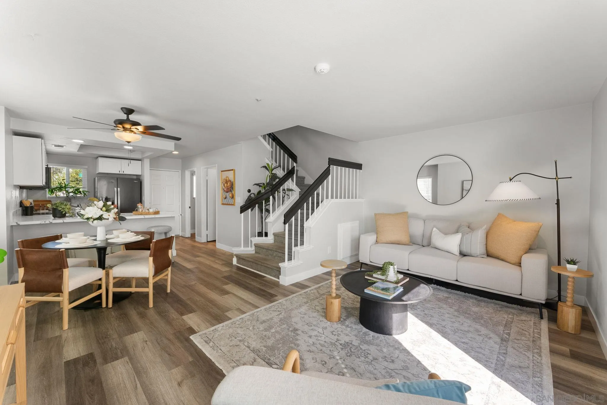 Open-plan living and dining room with a white sofa, kitchen island, and central staircase.