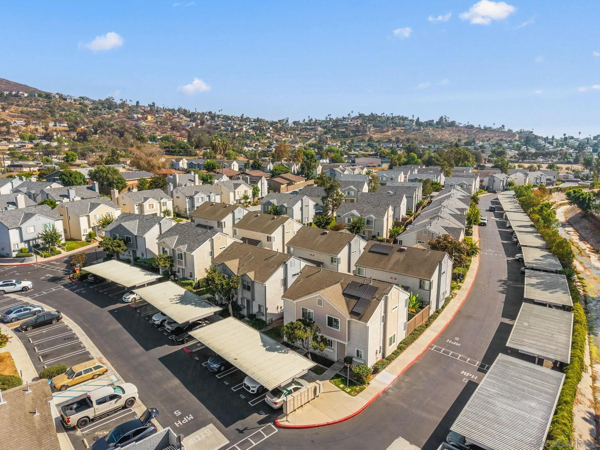 Aerial view of a residential community with rows of homes, covered parking, and solar panels.