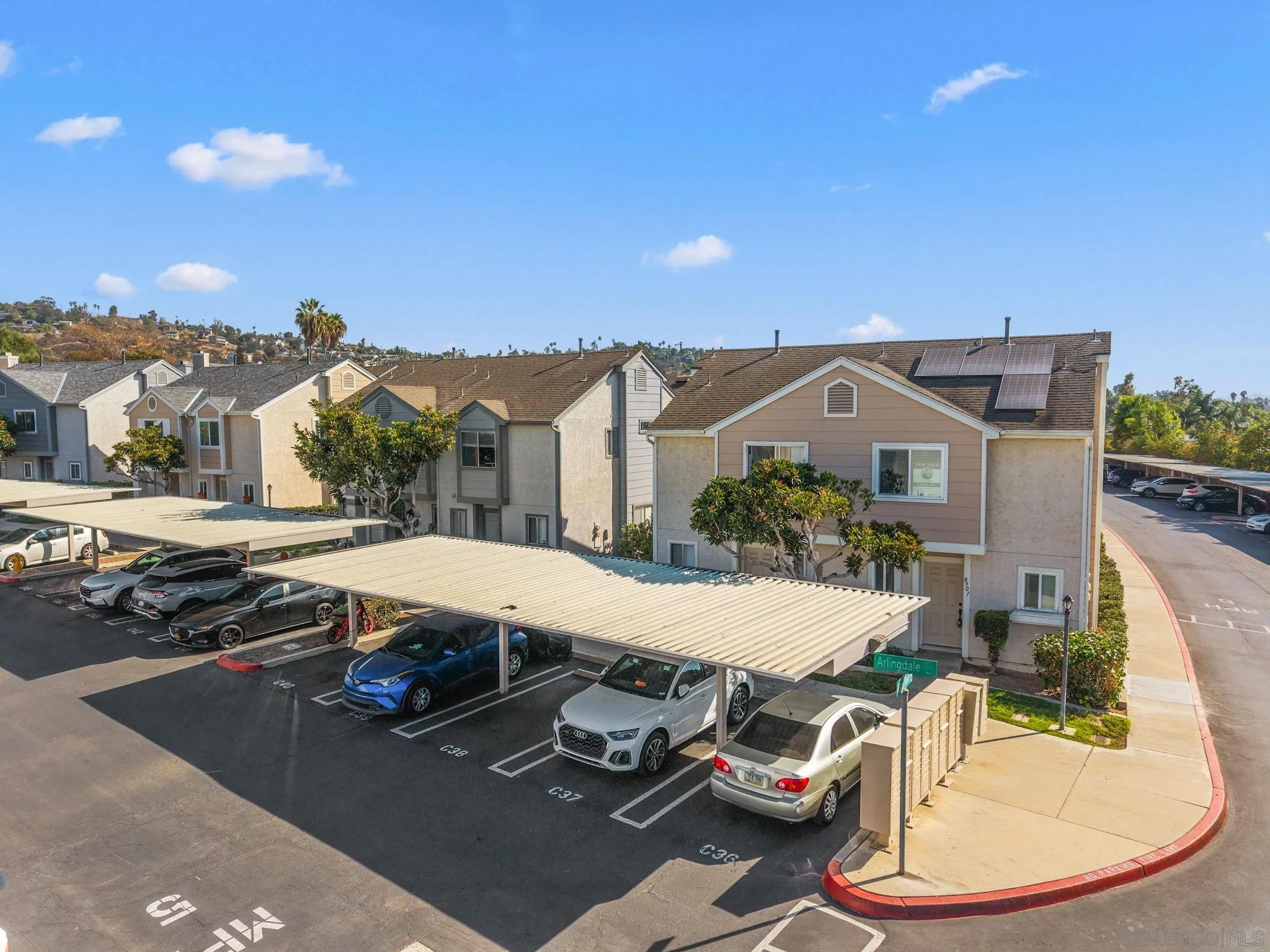 Tan attached home with rooftop solar panels above a covered parking area.