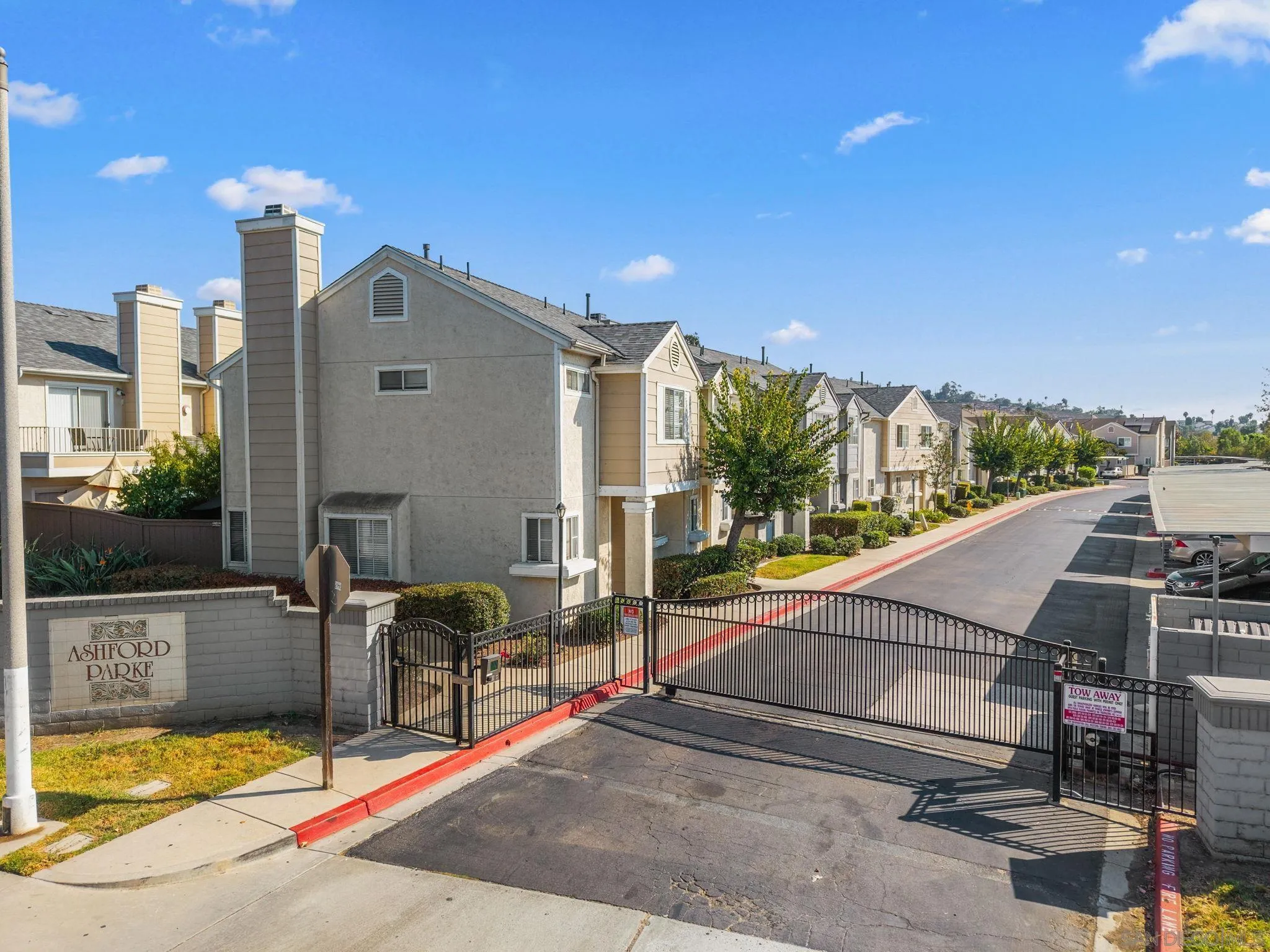 Gated townhouse community entrance with an Ashford Parke sign and homes lining the private drive.