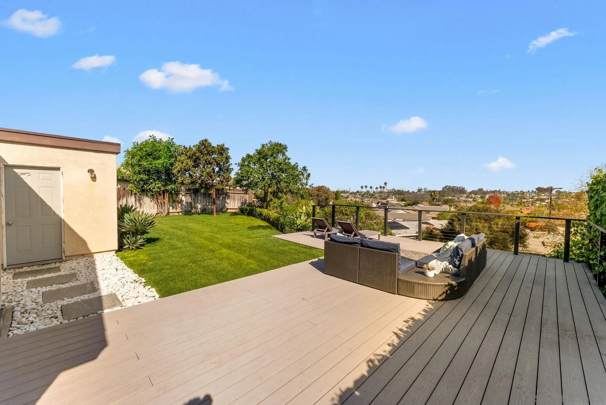 Backyard deck with outdoor lounge seating, a green lawn, and neighborhood views.