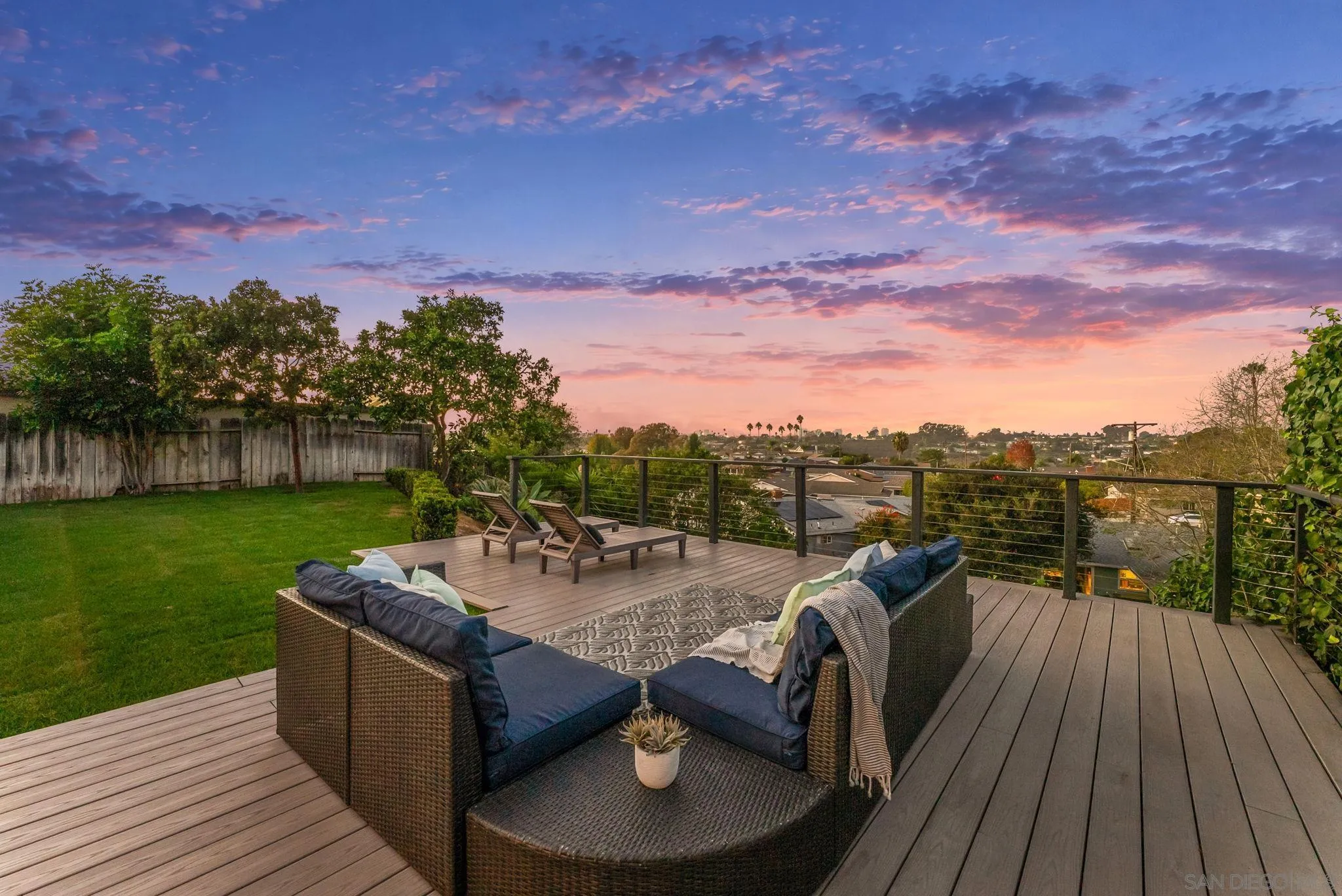 Furnished backyard deck with lounge seating and neighborhood views at sunset.