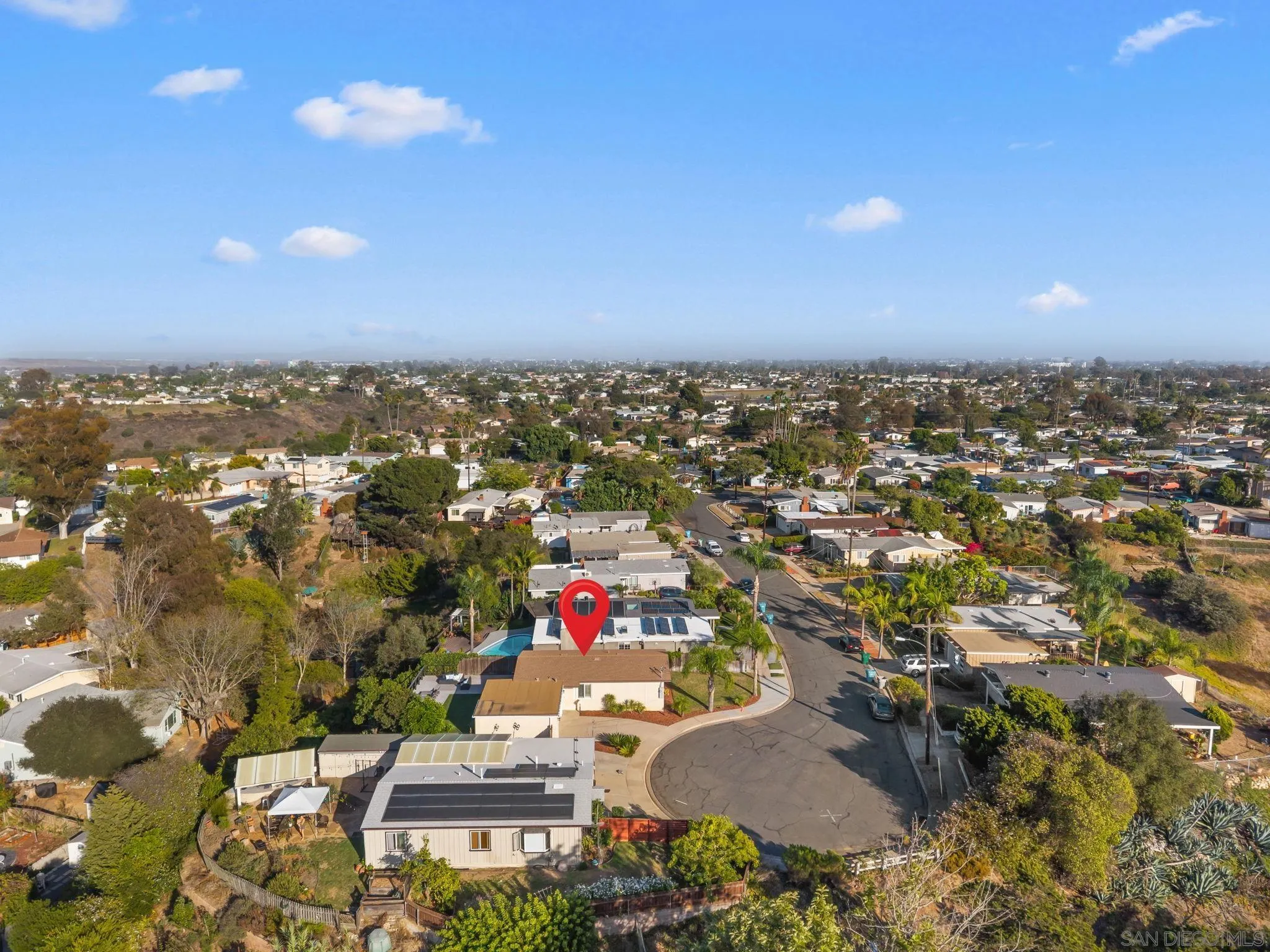 Aerial neighborhood view with a red pin marking a solar-panelled home near a cul-de-sac.
