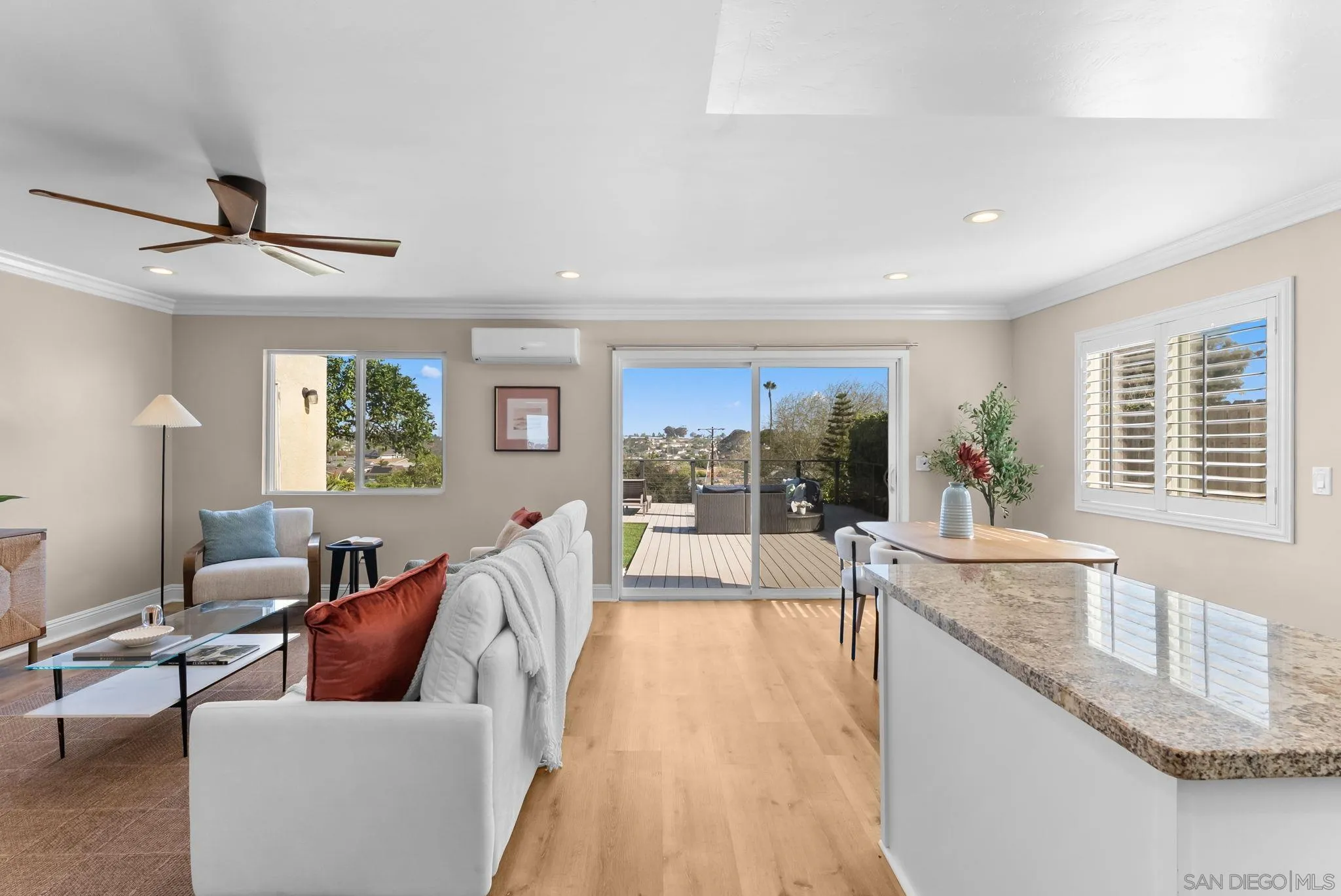 Open-plan living room and kitchen with a granite island and sliding doors to a deck.