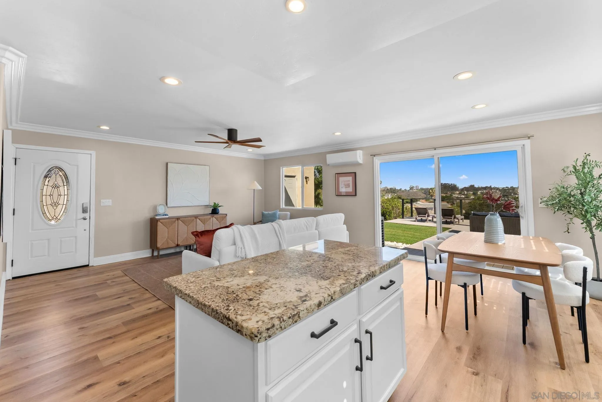 Open-plan kitchen, living, and dining area with a granite island and sliding doors to a patio.
