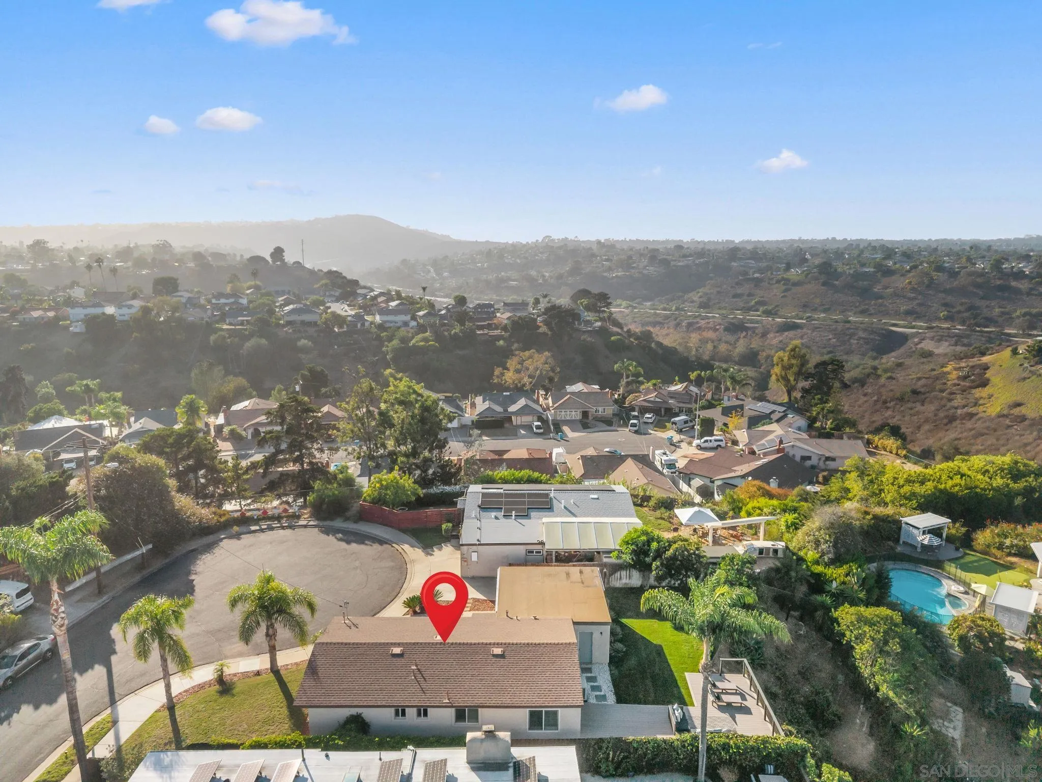 Aerial view of a cul-de-sac home with a red location marker and a nearby swimming pool.