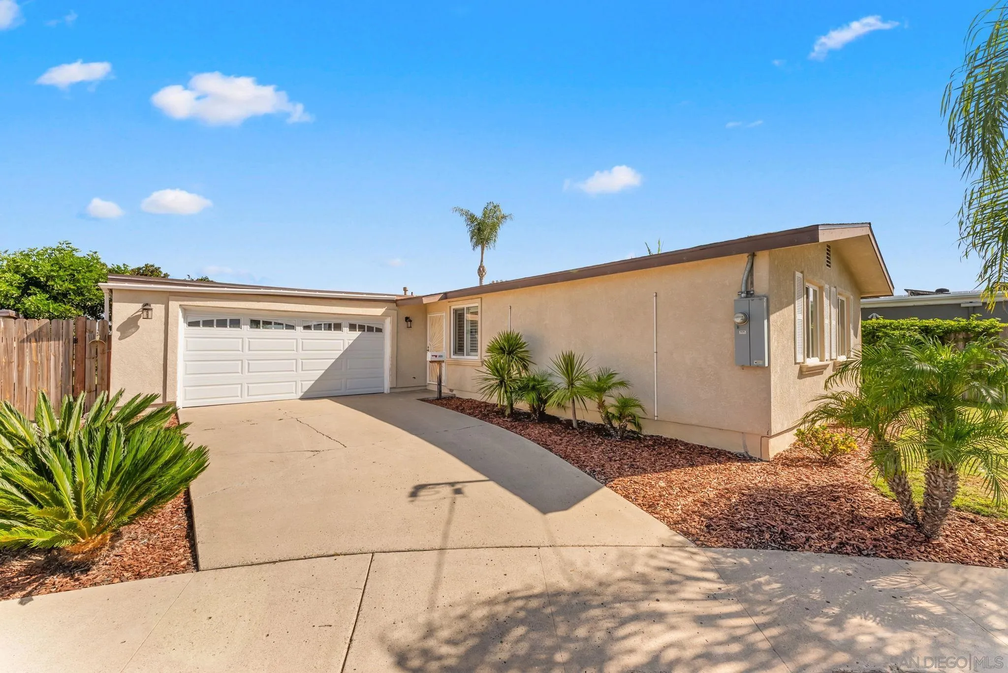 Single-story beige stucco home with a white garage and landscaped driveway.