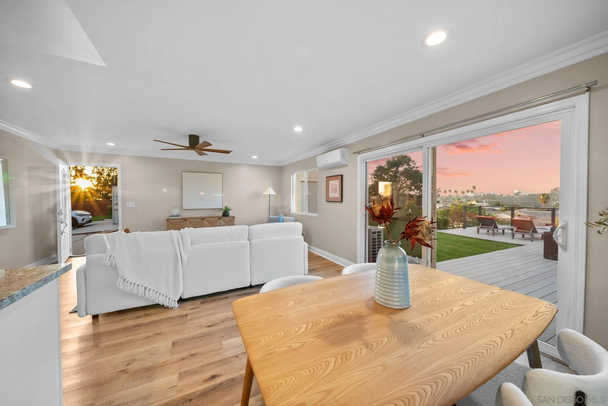 Open living and dining room with hardwood floors and sliding doors to a sunset-lit deck.