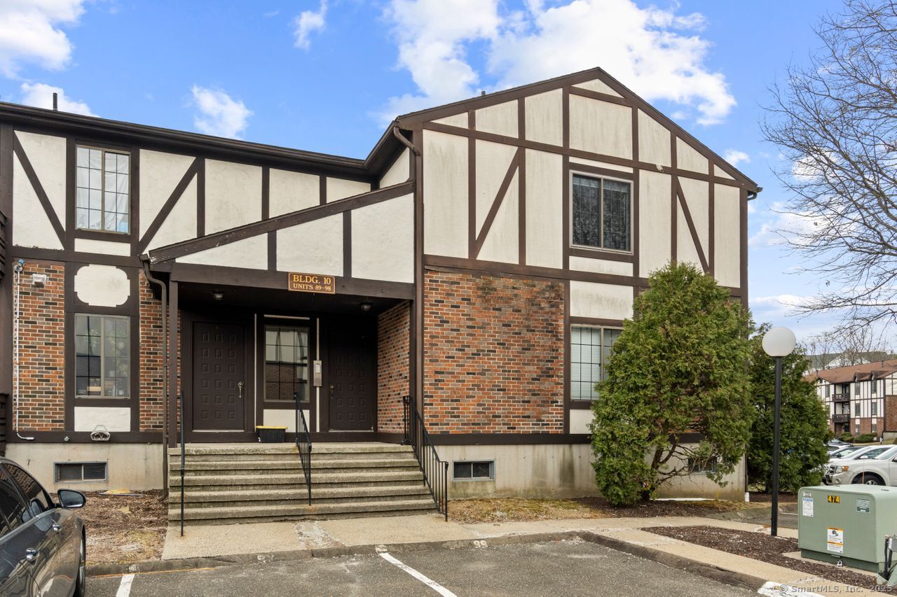 Multi-unit building with cream stucco, brick accents, and a covered entrance with concrete steps.