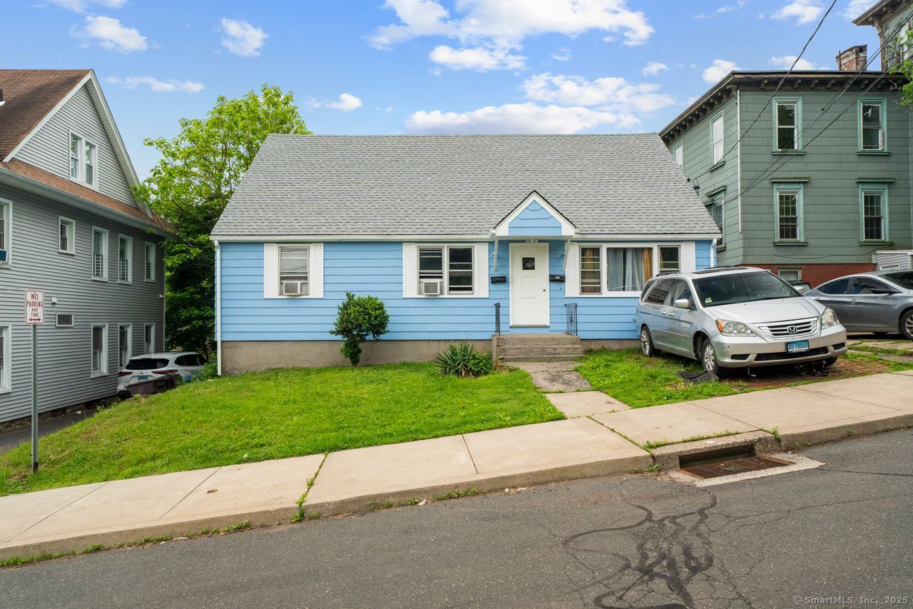Light-blue one-story house with white trim, a broad gray roof, and a small front lawn.