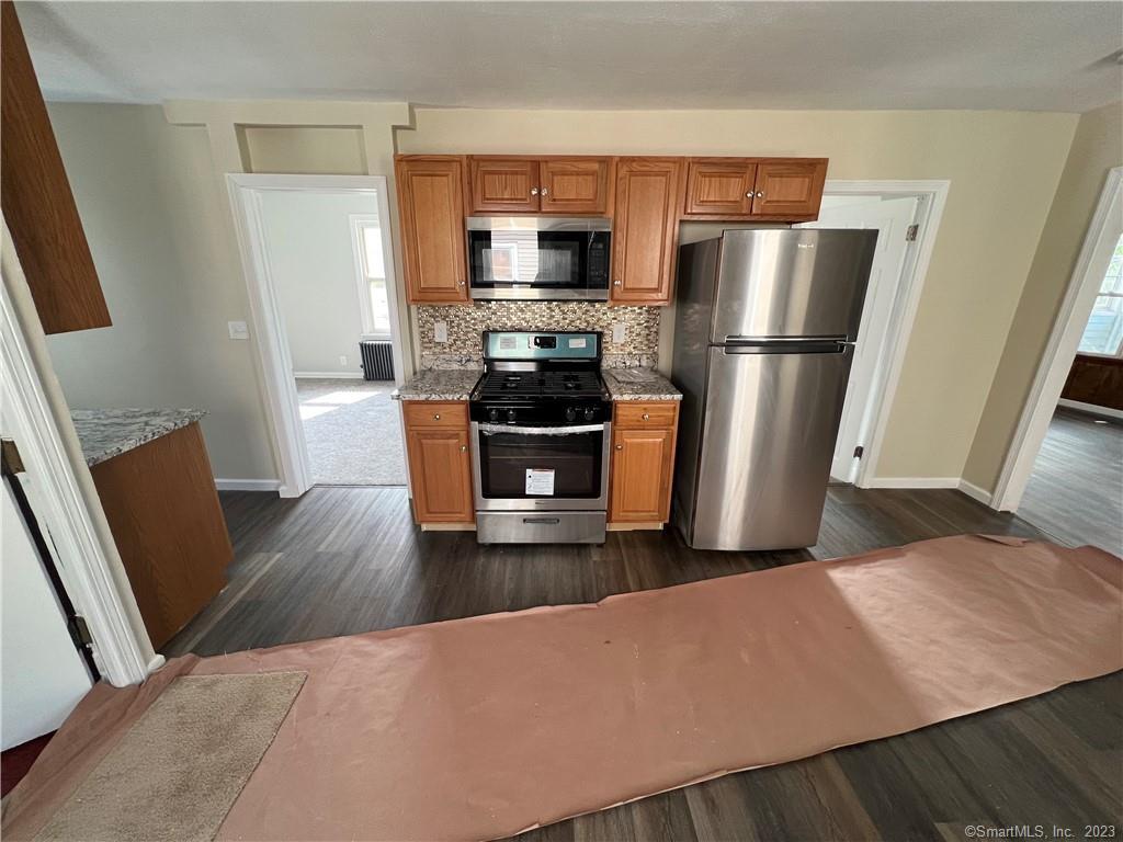 Kitchen with wood cabinets, stainless steel appliances, and protective floor covering.