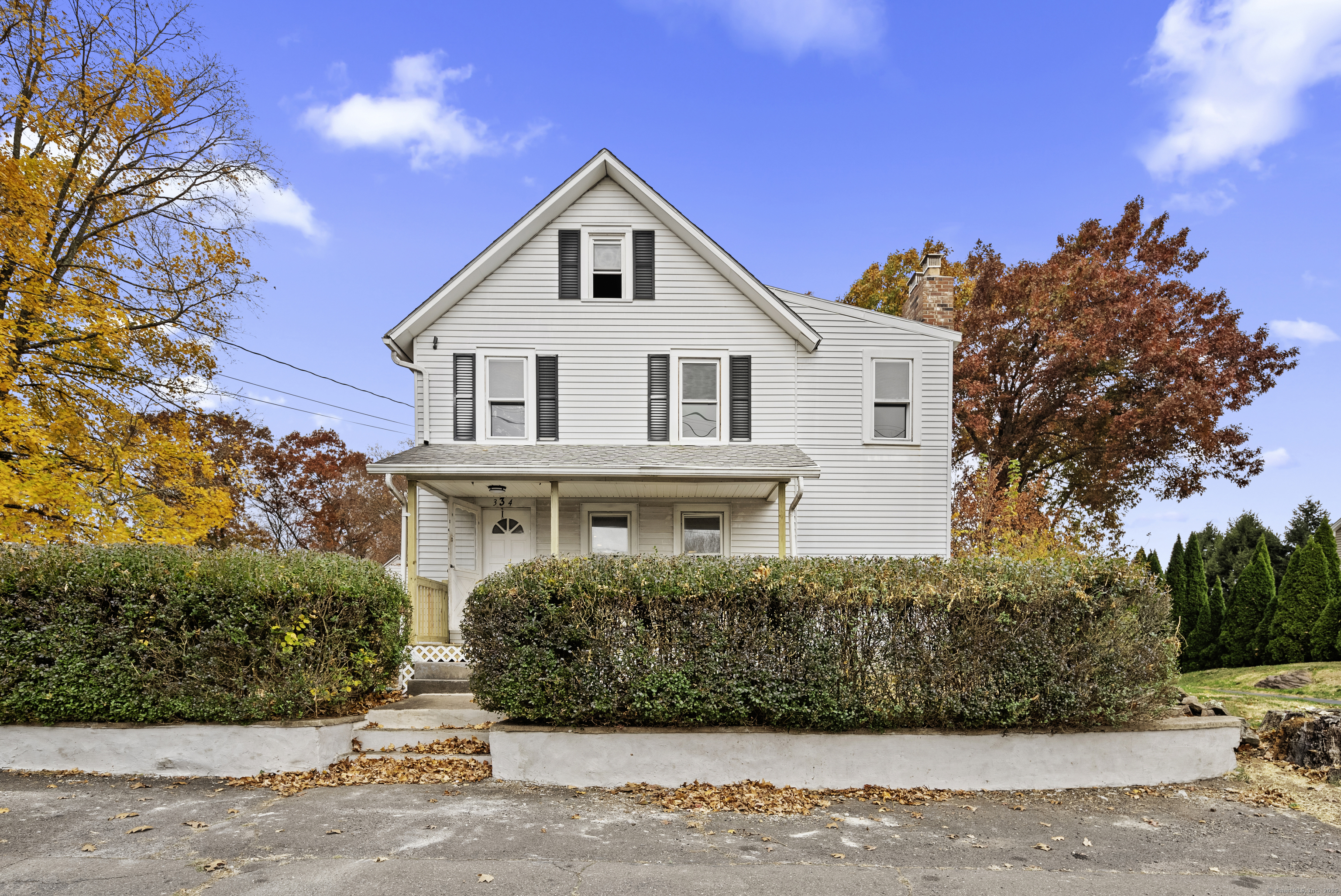 334 Gracey Avenue, a white two-story house with black shutters, a covered porch, and autumn foliage.