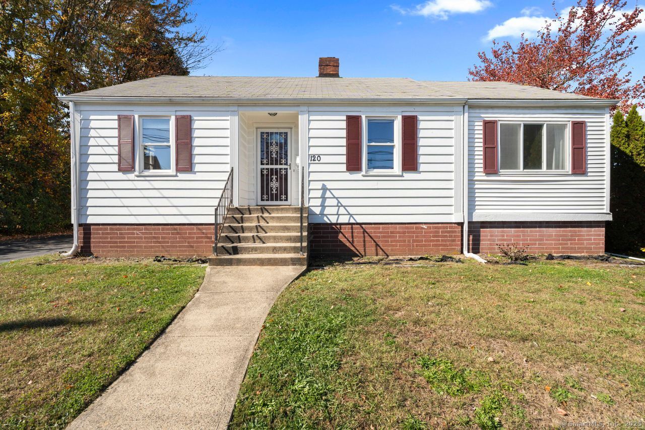 White one-story house with red shutters, brick foundation, and a walkway to the front steps.