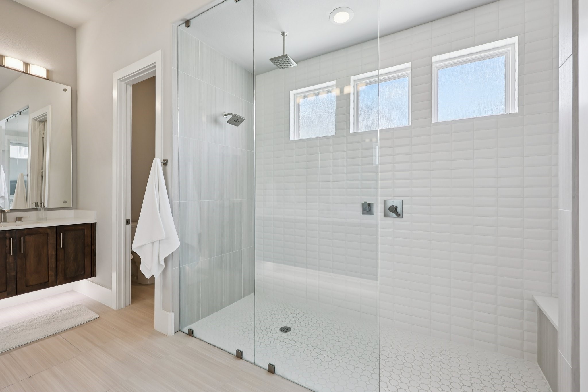Bathroom with a glass-enclosed tiled walk-in shower, three frosted windows, and a dark wood vanity.