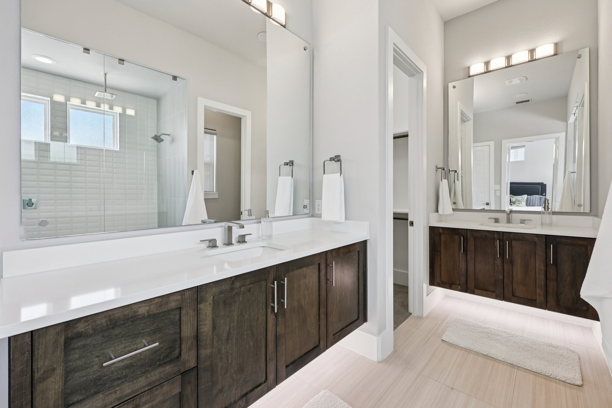 Modern bathroom with a dark wood double vanity and glass-enclosed shower.