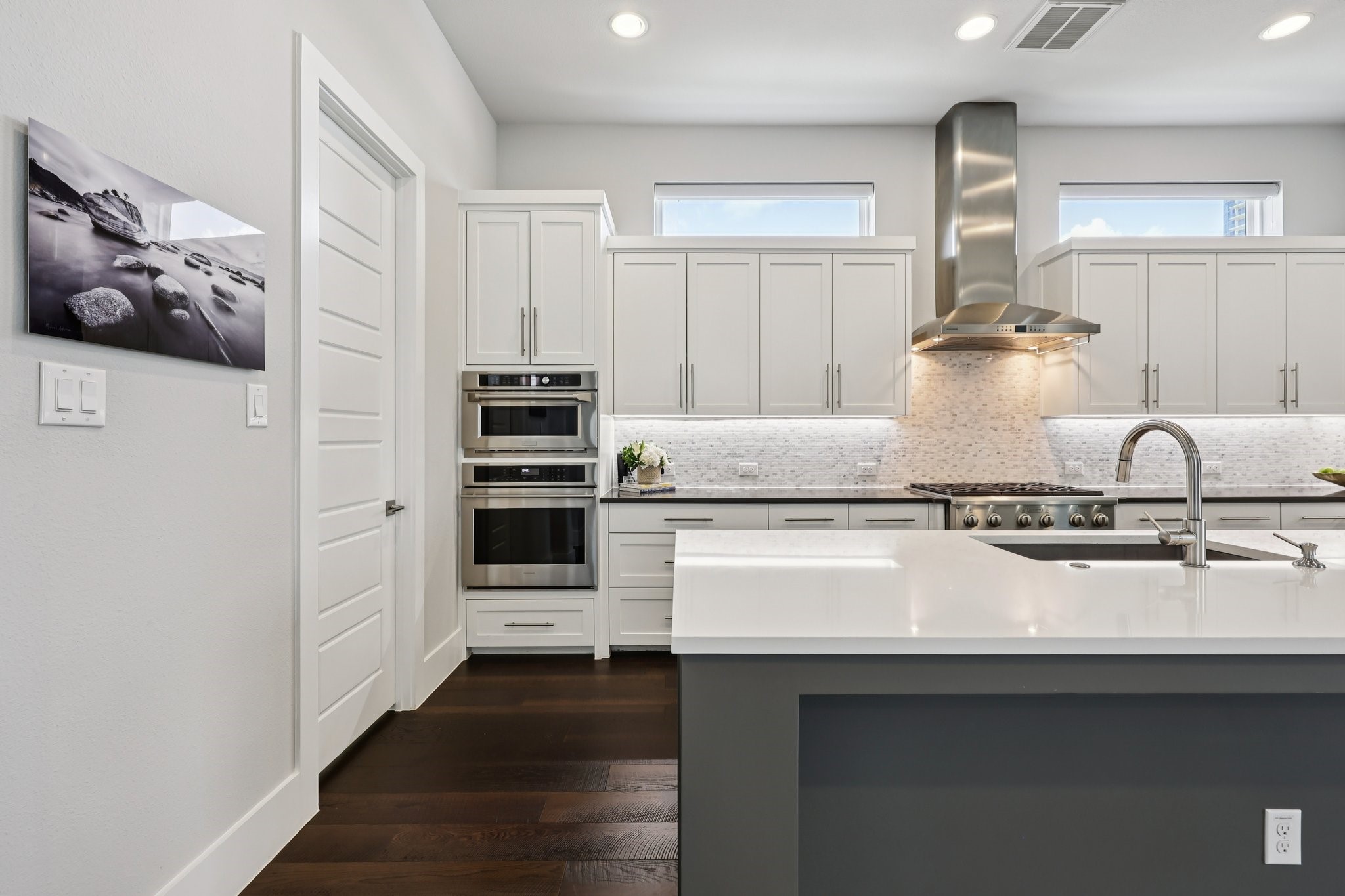 Modern kitchen with white cabinets, stainless steel appliances, and a large island with an inset sink.