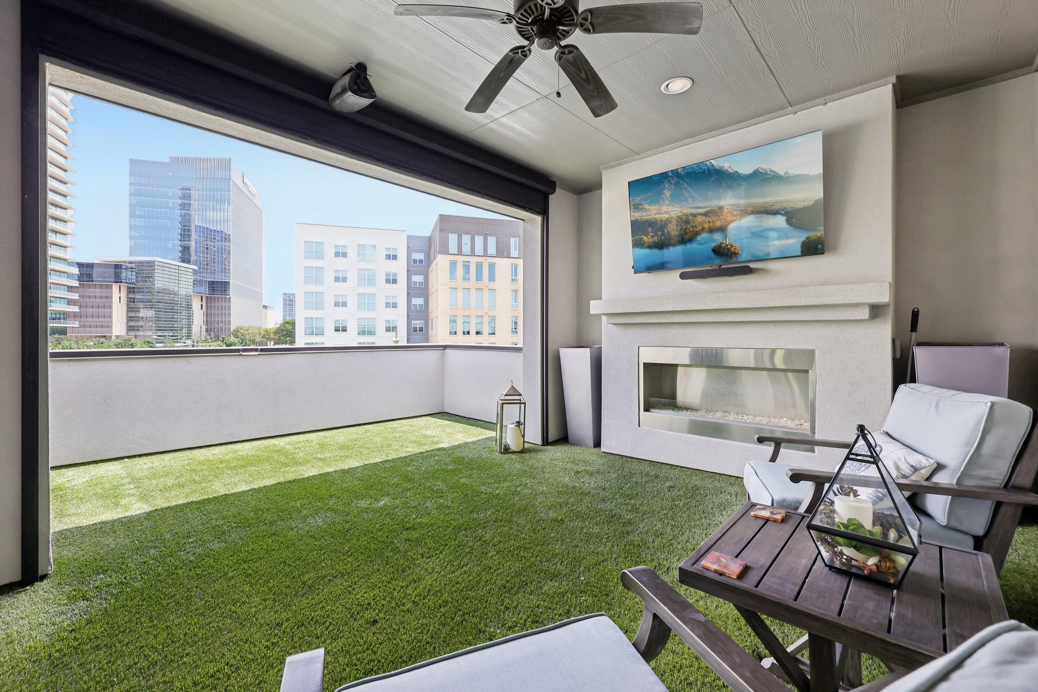 Rooftop terrace with artificial grass, a built-in fireplace, lounge seating, and city views.