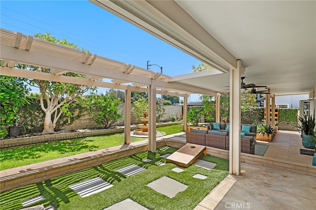Backyard patio with pergola, outdoor seating, lawn stepping stones, and a tiered fountain.