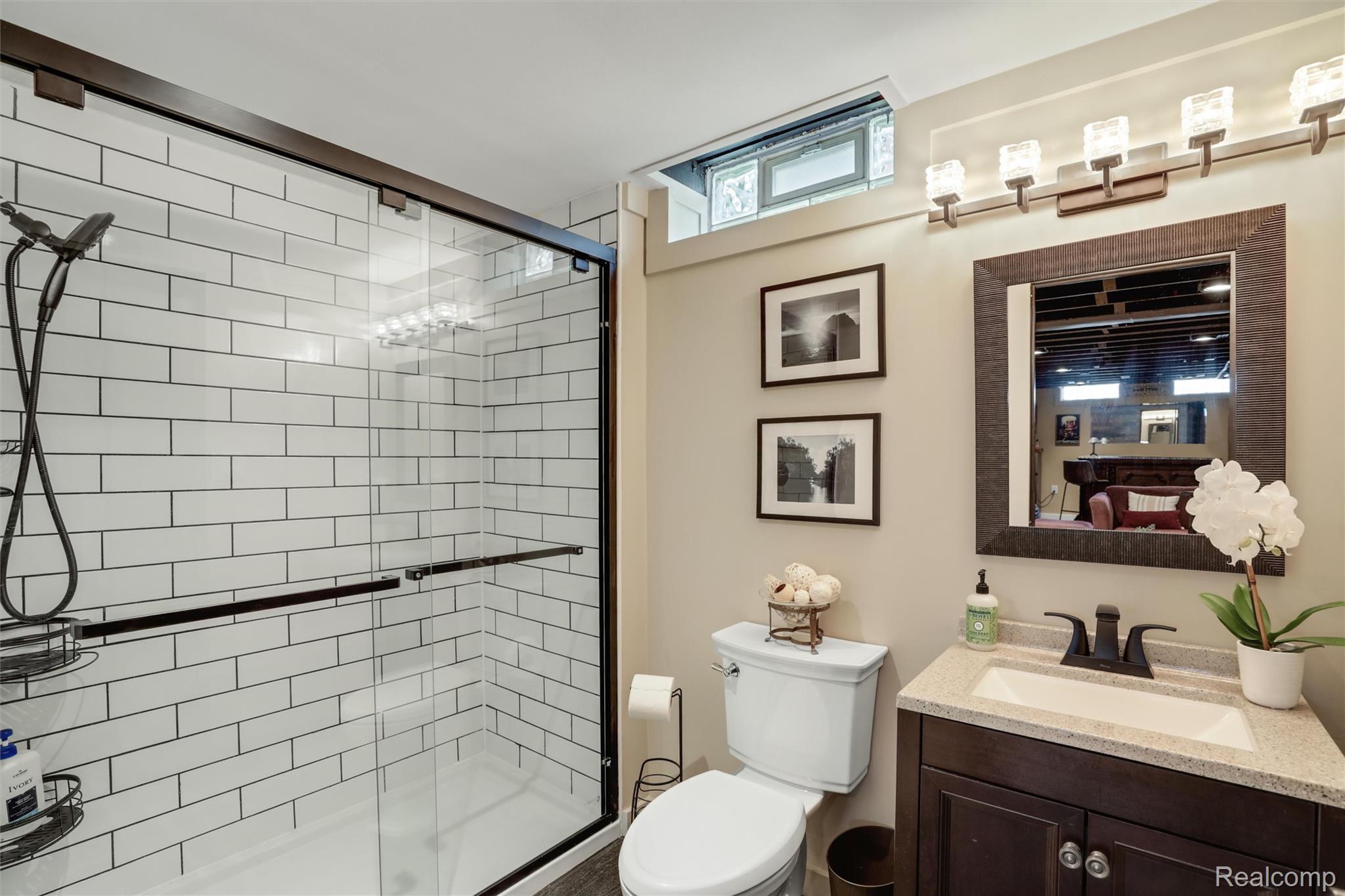 Bathroom with a glass-enclosed subway-tile shower and dark wood vanity.