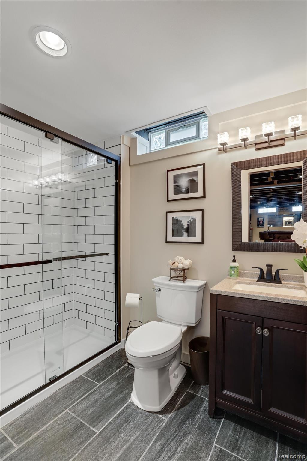 Bathroom with a glass subway-tile shower, dark gray floors, and a dark wood vanity.