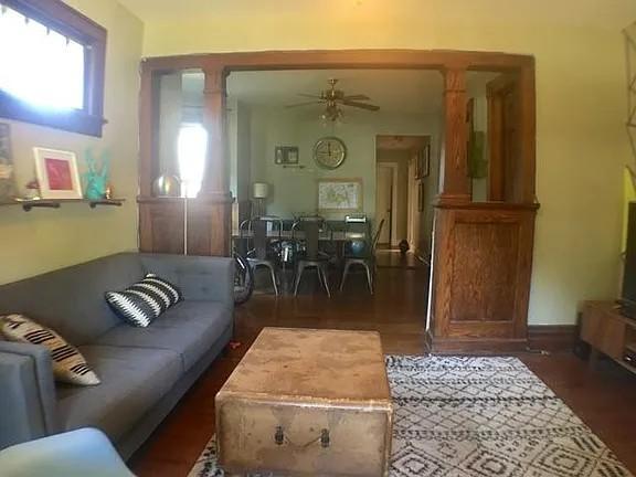 Living room with a gray sofa, trunk coffee table, patterned rugs, and a wood-trimmed dining-room opening.