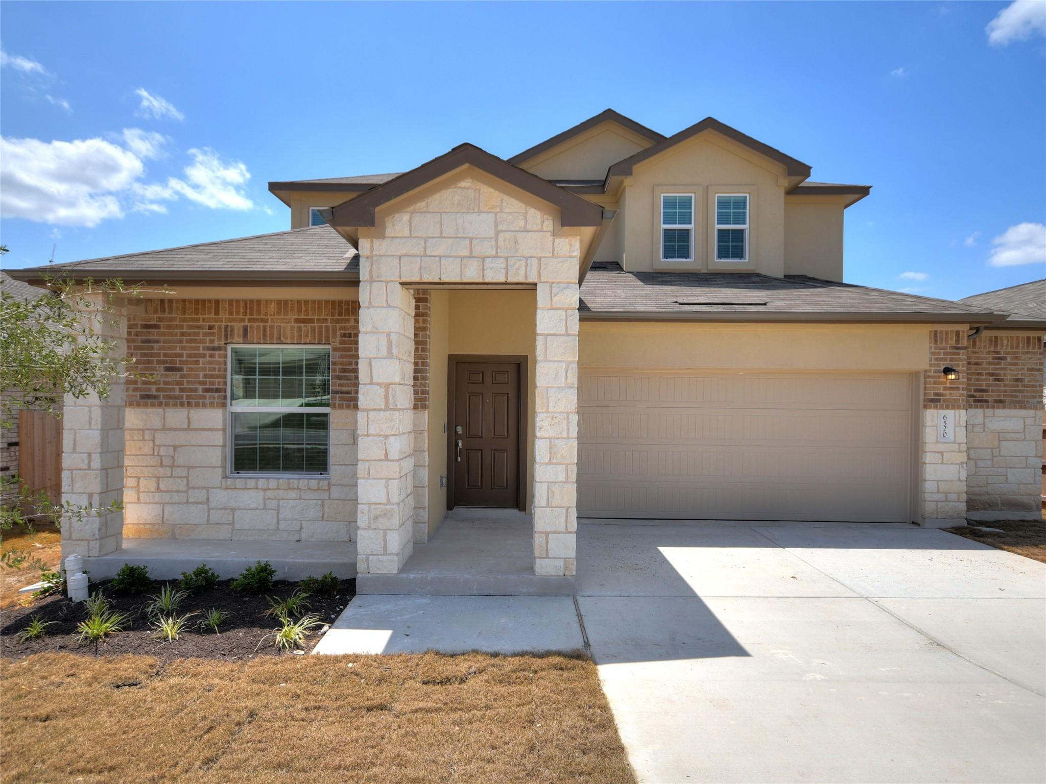 Two-story stone-and-brick home with a covered entry and attached garage.