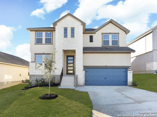 Two-story house with a stone entry tower, blue garage door, and front lawn.