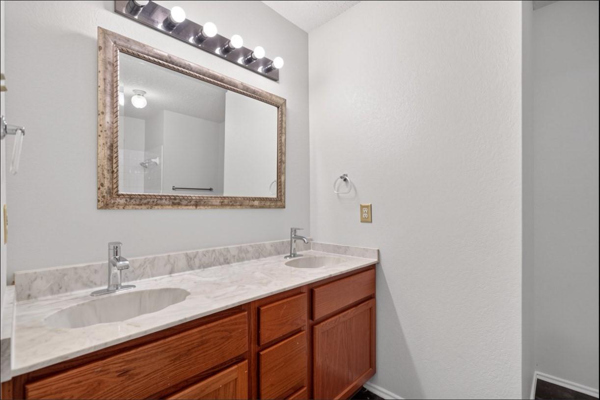 Bathroom double vanity with a marble-pattern countertop, wood cabinets, and framed mirror.
